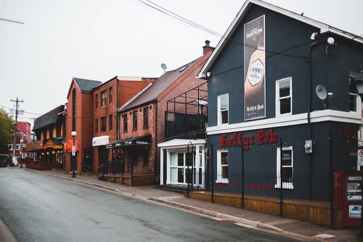 Aged and contemporary building facades with signboard near empty asphalt roadway under sky in town