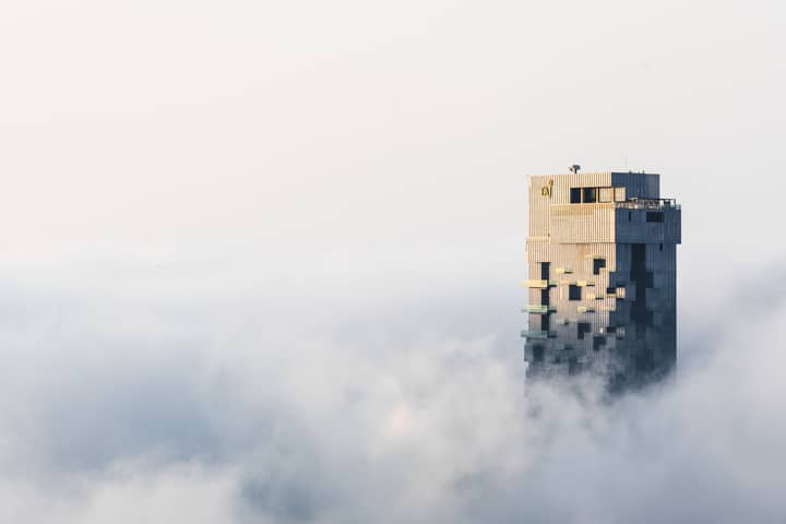 A skyscraper towers above Dubai's foggy skyline, capturing the serene majesty of urban architecture.