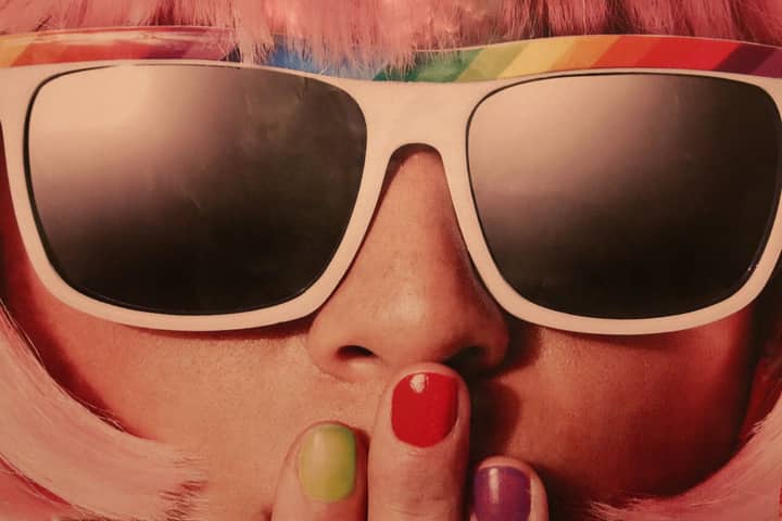 Fashionable woman with colorful sunglasses and nails in a retro style close-up.