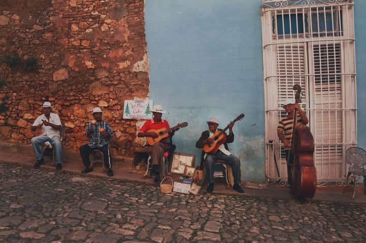 Street musicians performing in Trinidad, Cuba, showcasing traditional Cuban music against a vibrant blue wall.
