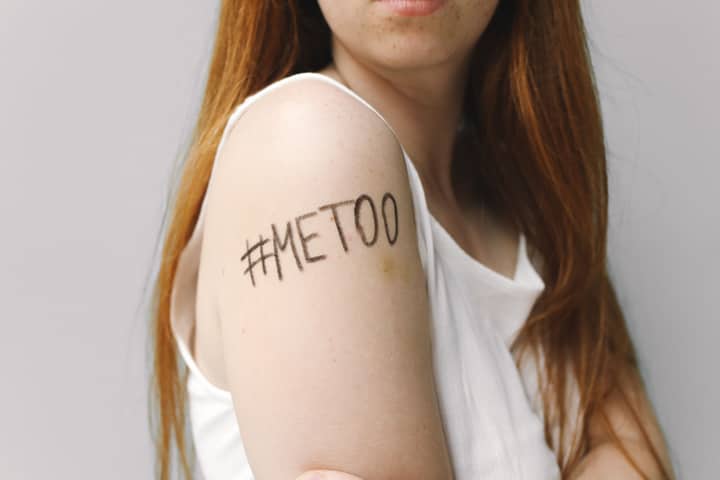 Close-up of a woman with #MeToo written on her arm, symbolizing empowerment and solidarity.