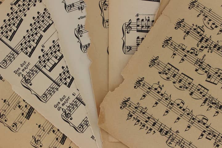 Close-up of vintage sheet music with torn edges, highlighting musical notations and history.
