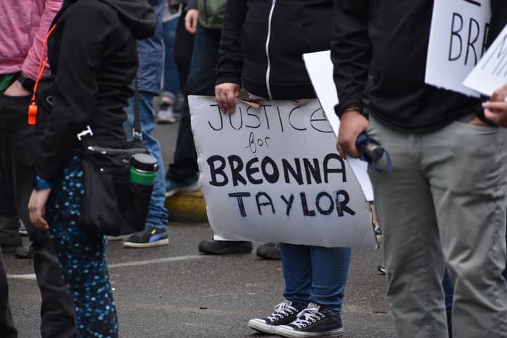 A peaceful protest advocating justice for Breonna Taylor with participants holding signs outdoors.