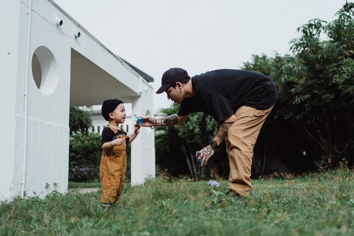 A joyful moment of a father and son playing with bubbles in a garden setting.