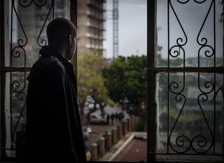 A man gazes out a window, capturing a thoughtful moment in Lusaka's urban landscape.