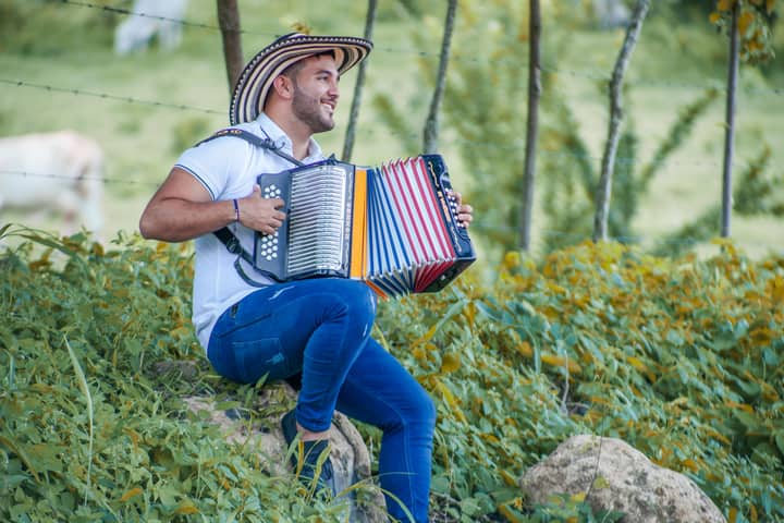 A Colombian musician enjoying playing the accordion in a lush outdoor setting in Ovejas, Sucre.