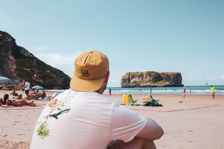 Man enjoying a sunny day at Gulpiyuri Beach, Asturias, Spain. Perfect for beach lovers.