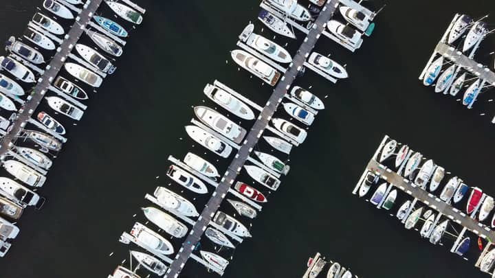 Drone shot capturing yachts and boats moored at marina piers, showcasing nautical lifestyle.
