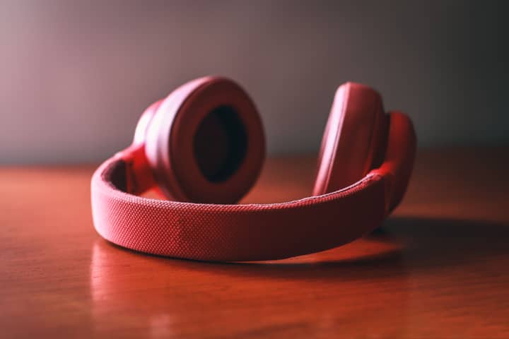 Close-up of vibrant red wireless headphones resting on a wooden surface.