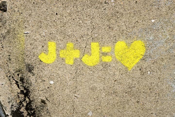 Yellow heart graffiti with initials J+J on concrete wall symbolizing love.