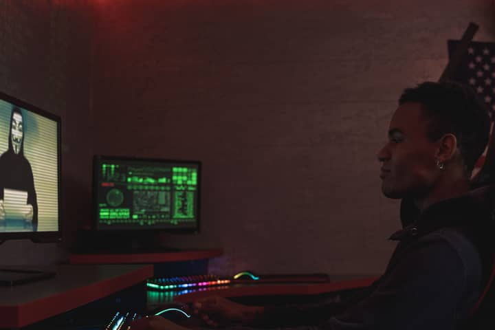 A cybersecurity professional monitors data systems in a dark room, emphasizing protection and vigilance.
