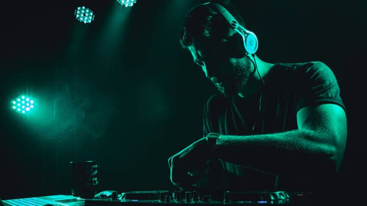 DJ mixes music live on stage with vibrant lighting creating an energetic atmosphere.