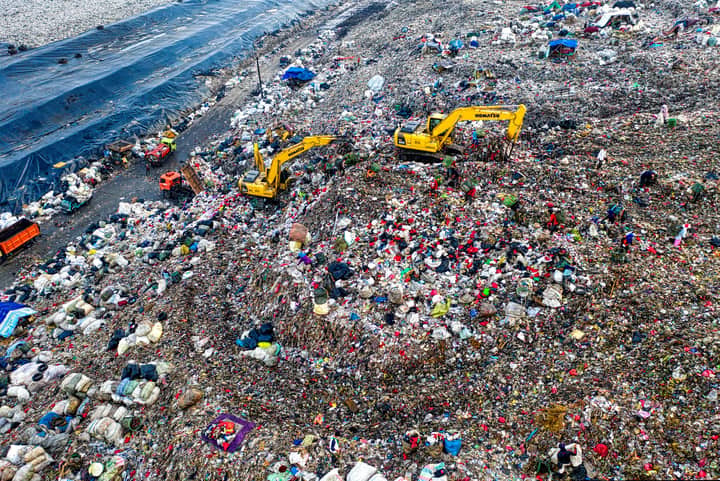 Aerial shot of a landfill in West Java with excavators and piles of trash, highlighting environmental issues.