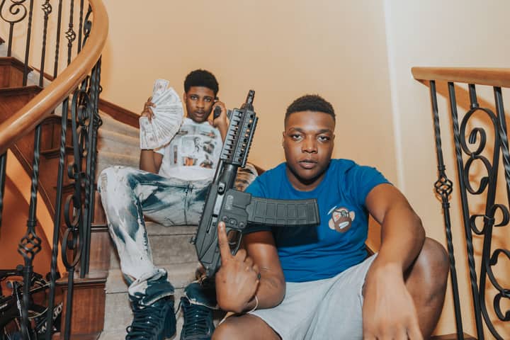 Two young men sitting on a staircase holding cash and a weapon in Las Vegas.