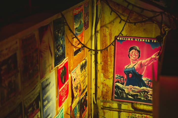 High angle of different placards of musical group on metal walls of weathered construction