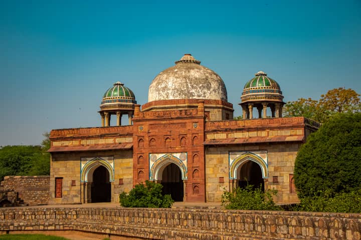 Isa Khan's Tomb with intricate architecture under a clear blue sky in Delhi, India.