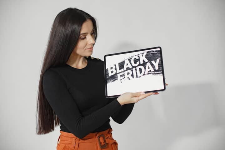 Woman with long black hair holding a tablet displaying 'Black Friday' against a white background.