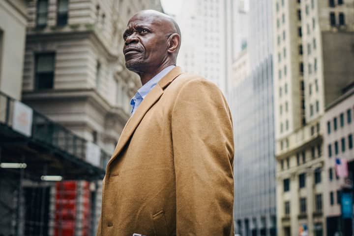 Side view of bald middle aged African American male entrepreneur looking away between modern multistage houses in city