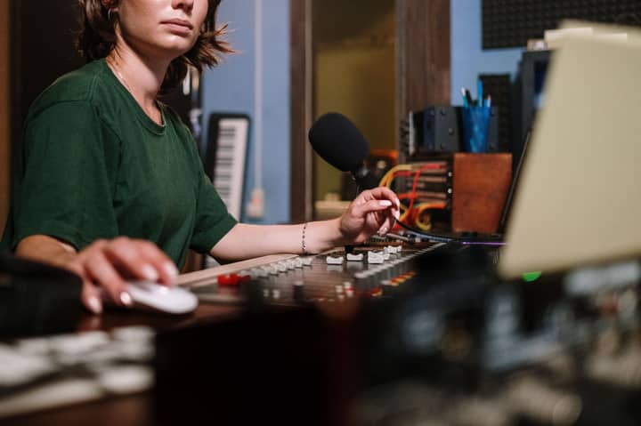 A sound technician using an audio mixer and computer in a modern recording studio.