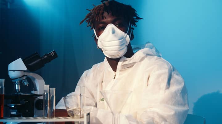 Scientist in protective gear using a microscope for research in a laboratory.
