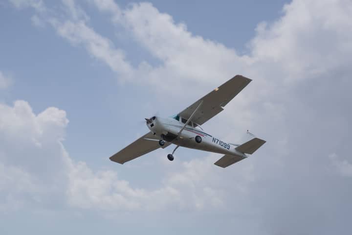 Cessna 182 airplane soaring through a bright blue sky in Austin, Texas.
