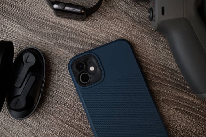 A collection of modern gadgets including a smartphone, smartwatch, and earphones placed on a textured wooden surface.