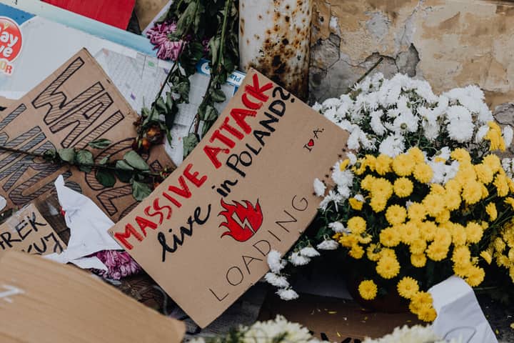 Protest sign with flowers during demonstration in Poland, highlighting social issues.