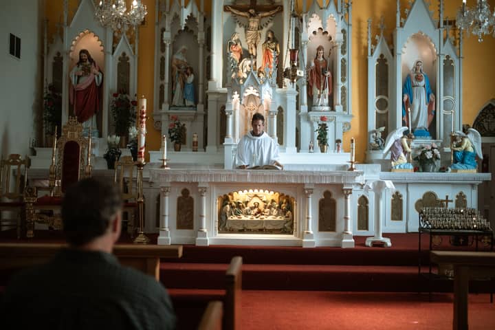A priest conducts mass at a beautifully decorated church altar, engaging the congregation.