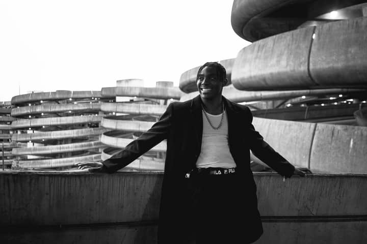 Fashionable man posing in an urban parking structure, exuding style.