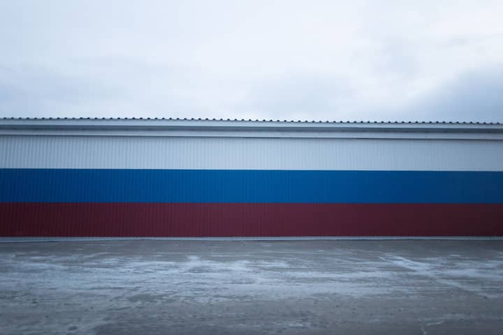 Stripes of red blue and white colors on modern building in town under cloudy gray gloomy sky