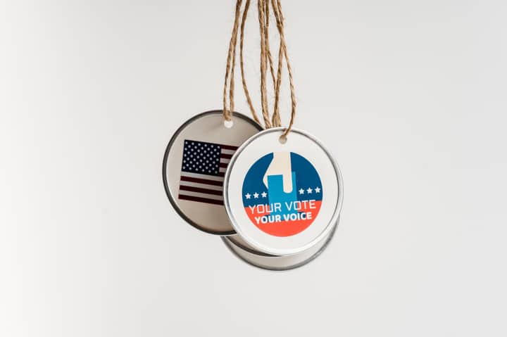 Close-up view of USA voting badges hanging on strings against a white background.