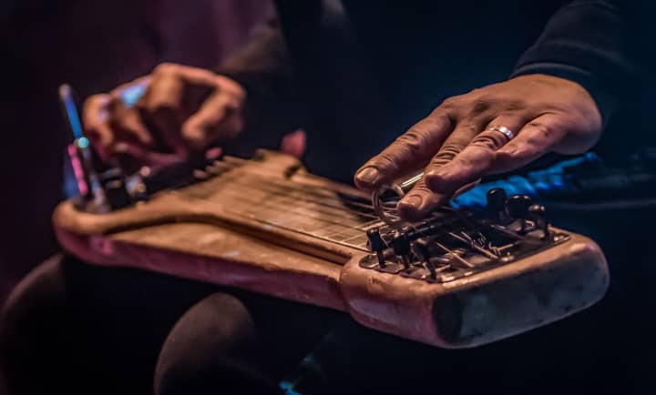Detailed shot of a musician playing a vintage lap steel guitar with a slide and ring.
