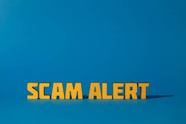 Bold yellow 'Scam Alert' text on a vivid blue surface, emphasizing warning and caution.