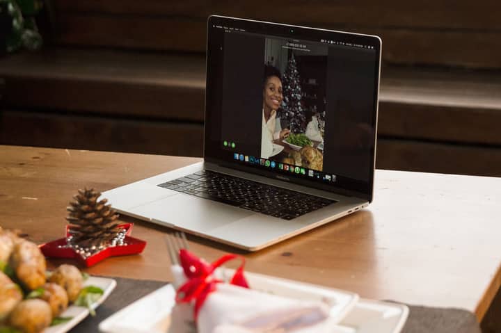 Laptop displaying a festive video call, showing a holiday dinner setting.