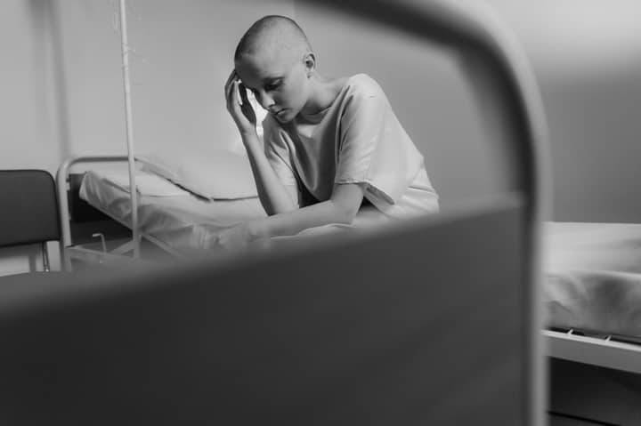Emotional black and white photo of a woman in a hospital setting, representing vulnerability and courage.