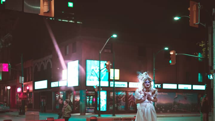 A dramatic urban night scene in London, Canada featuring a costumed individual.