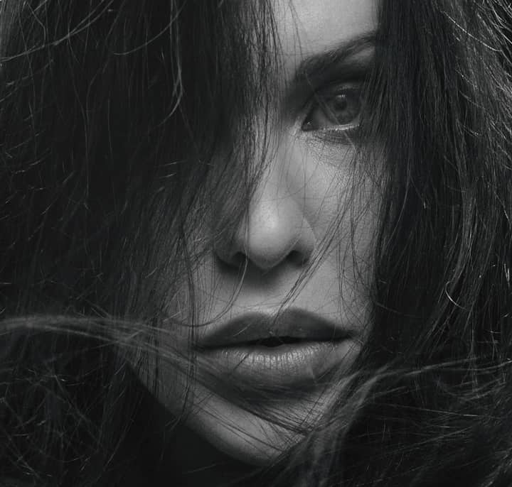 Striking grayscale close-up of a woman's face with hair framing her intense gaze.