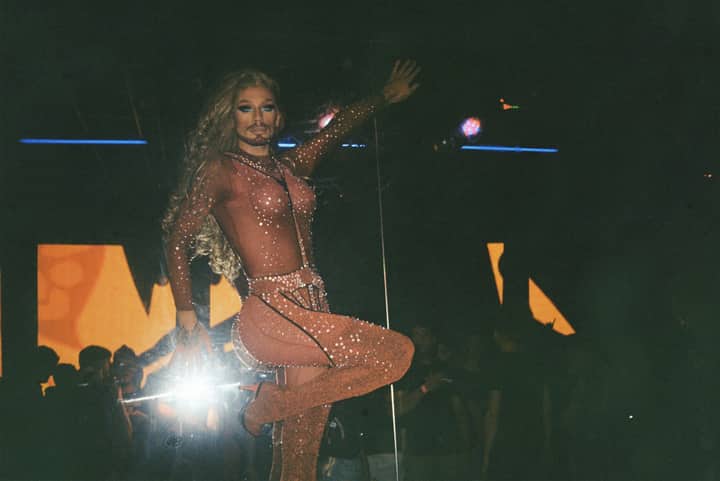A drag performer captivates the audience on a vibrant stage in a Lisbon nightclub.
