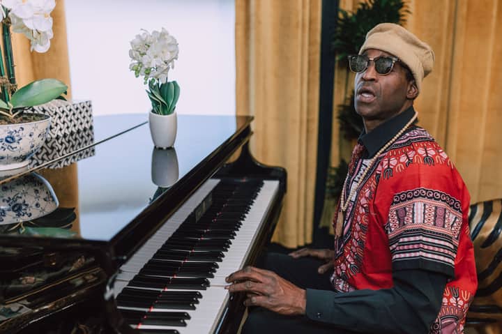 Stylish man in vibrant traditional clothing playing piano indoors. Capturing culture and music.