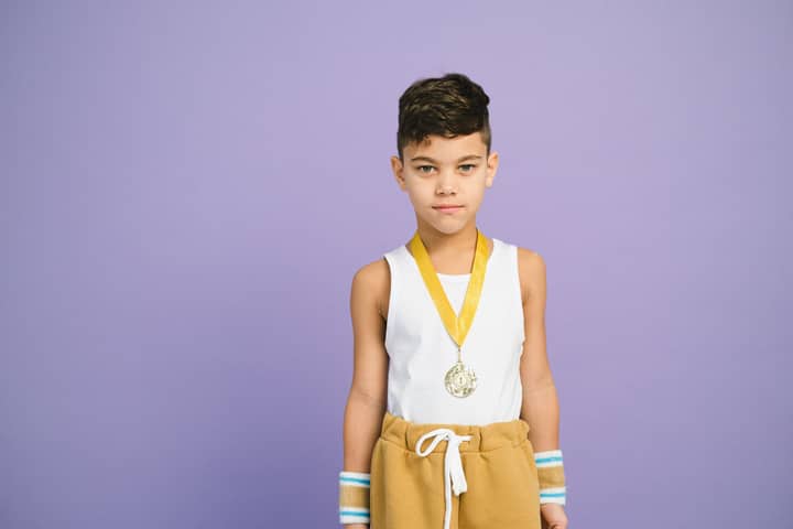 Confident young boy wearing a sports medal, symbolizing achievement and victory.