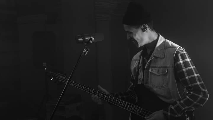 Grayscale image of a smiling musician playing bass guitar.
