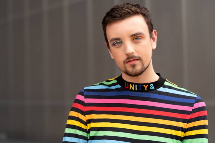 A colorful portrait of a person wearing a rainbow-striped top, symbolizing unity and diversity.