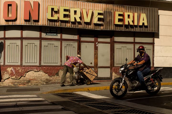 A moment in Caracas showcasing urban life with a motorcyclist and street vendor.