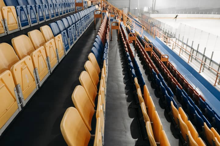 An indoor ice rink with empty stadium seating, perfect for events.