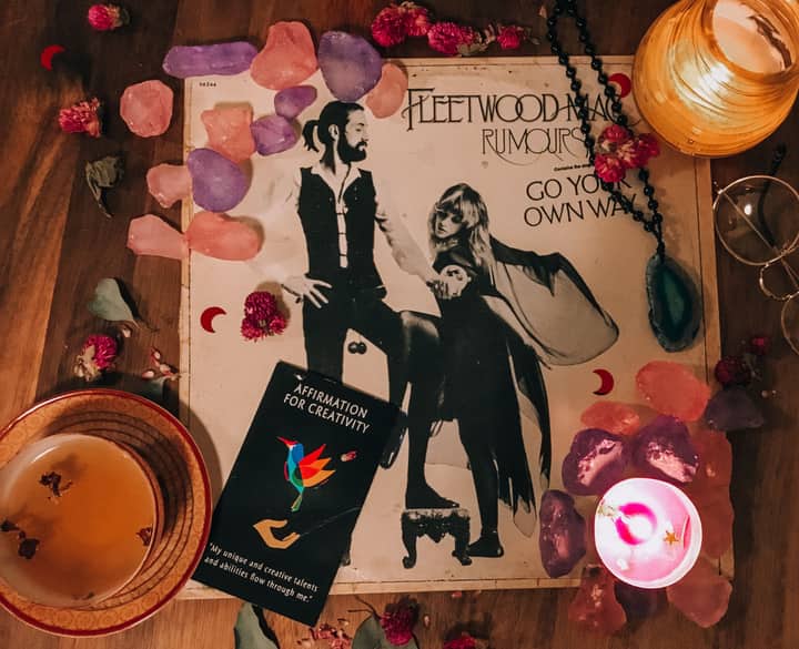 A cozy and artistic setup featuring a Fleetwood Mac vinyl, candles, and creative affirmations.
