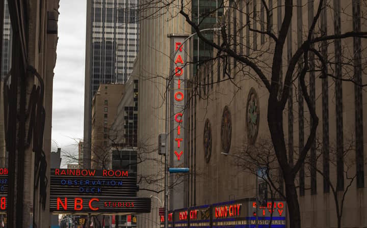 View of Radio City and NBC Studios signs in New York City featuring prominent neon lights.
