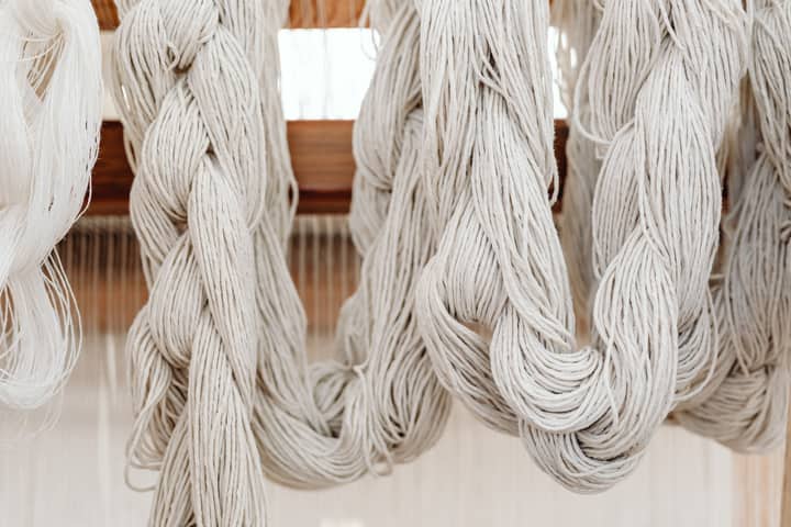 Close-up of braided yarn hanks hanging on a loom, showcasing traditional weaving craftsmanship.