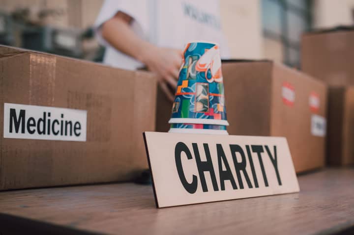 Close-up of charity boxes labeled for donation, featuring medicine and colorful paper cups.