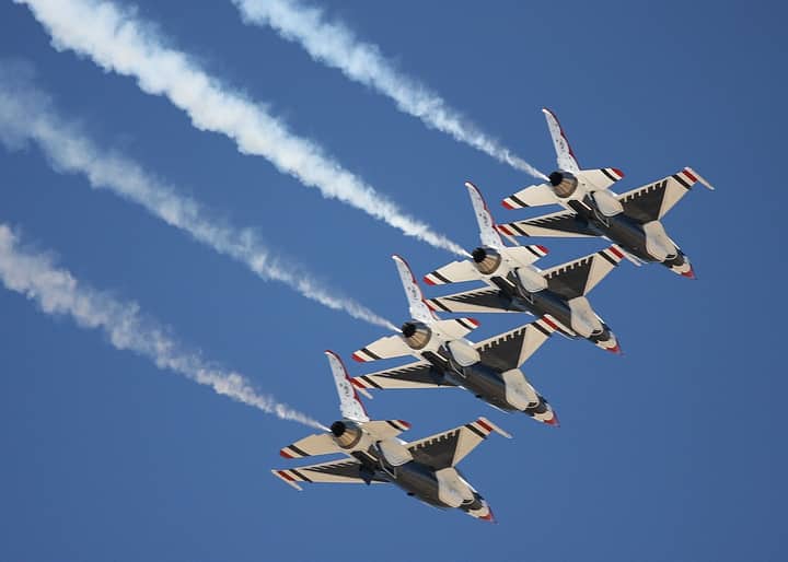 Four fighter jets performing a precise aerial formation with vapor trails against a clear blue sky.