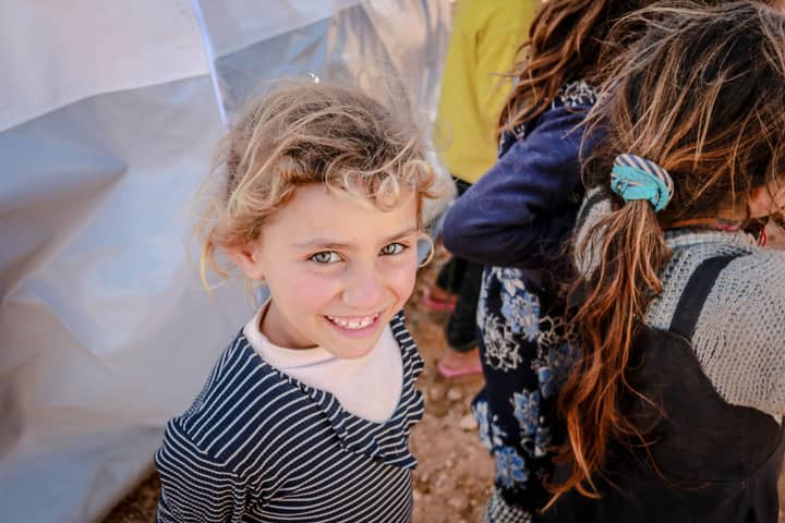 From above of cheerful girl smiling and looking at camera among crop anonymous friends